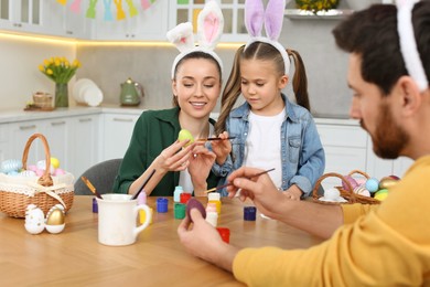 Photo of Family painting Easter eggs at table in kitchen