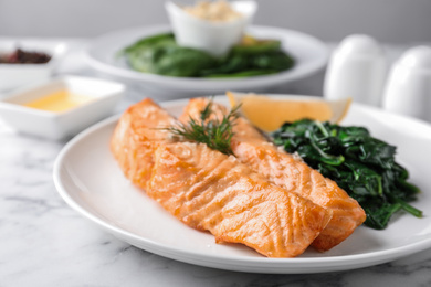 Photo of Tasty salmon with spinach and lemon on table