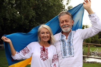 Photo of Happy mature couple with national flag of Ukraine outdoors