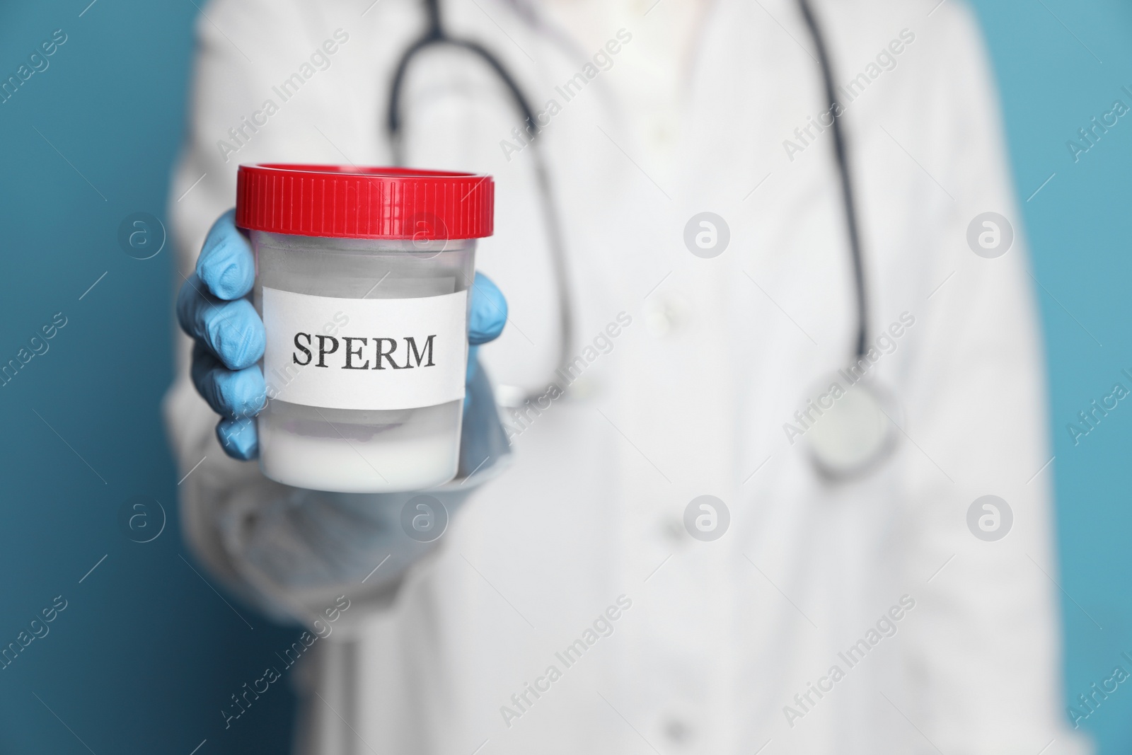 Photo of Doctor holding container with sperm on turquoise background, closeup. Space for text