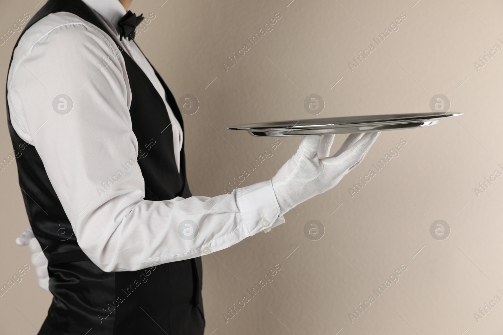 Photo of Butler with tray on beige background, closeup