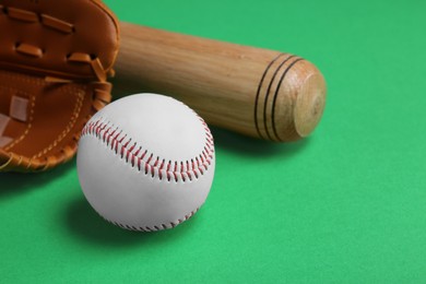 Baseball glove, bat and ball on green background, closeup. Space for text