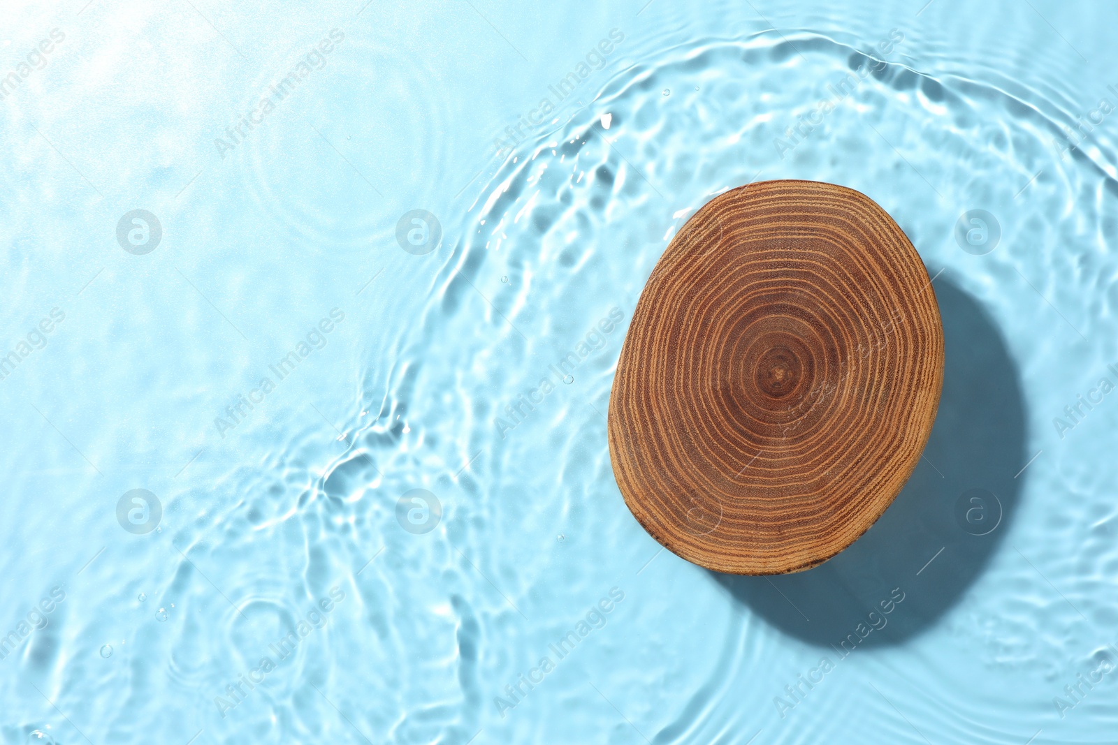 Photo of Presentation of product. Wooden podium in water on light blue background, top view. Space for text