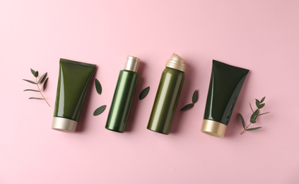 Flat lay composition with cosmetic products and leaves on pink background