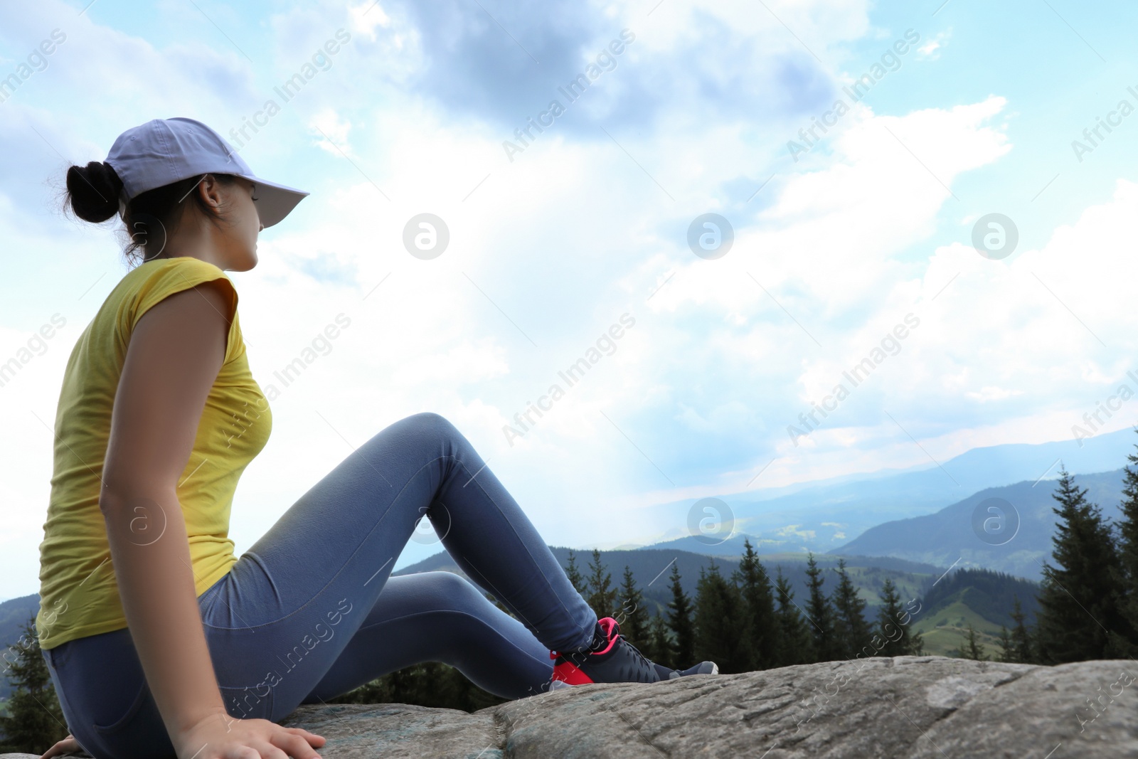 Photo of Female hiker on rocky mountain near forest. Space for text