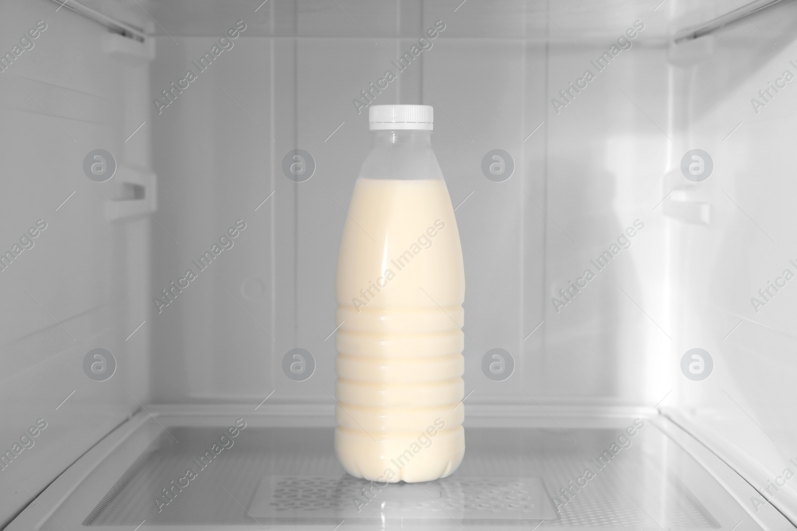 Photo of Bottle of milk on shelf inside modern refrigerator