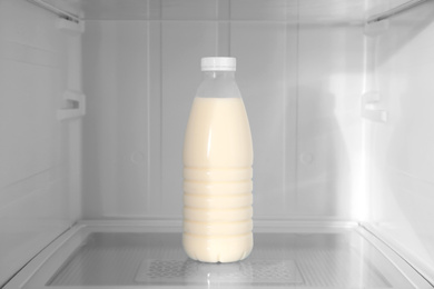 Photo of Bottle of milk on shelf inside modern refrigerator