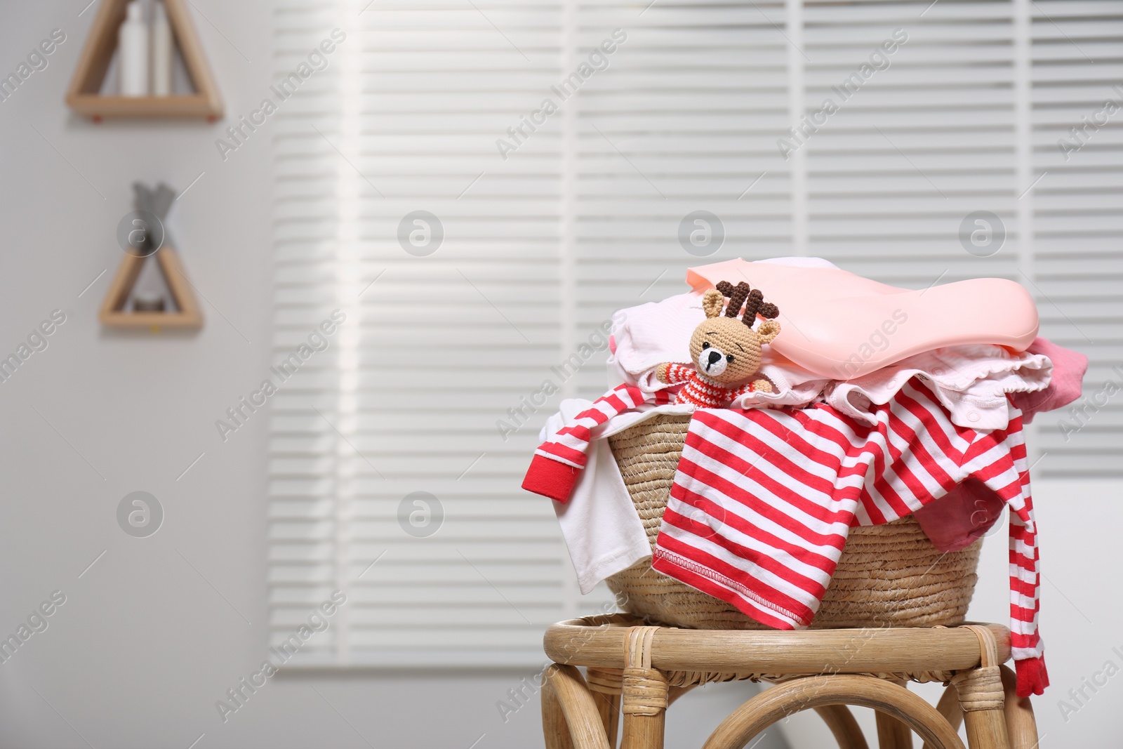 Photo of Laundry basket with baby clothes and crochet toy indoors, space for text