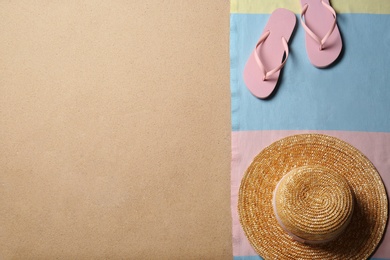 Photo of Straw hat, flip flops and space for text on beach sand, top view. Summer vacation