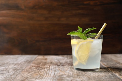 Photo of Natural lemonade with mint in glass on wooden table