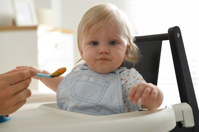 Photo of Mother feeding her cute little baby with healthy food at home