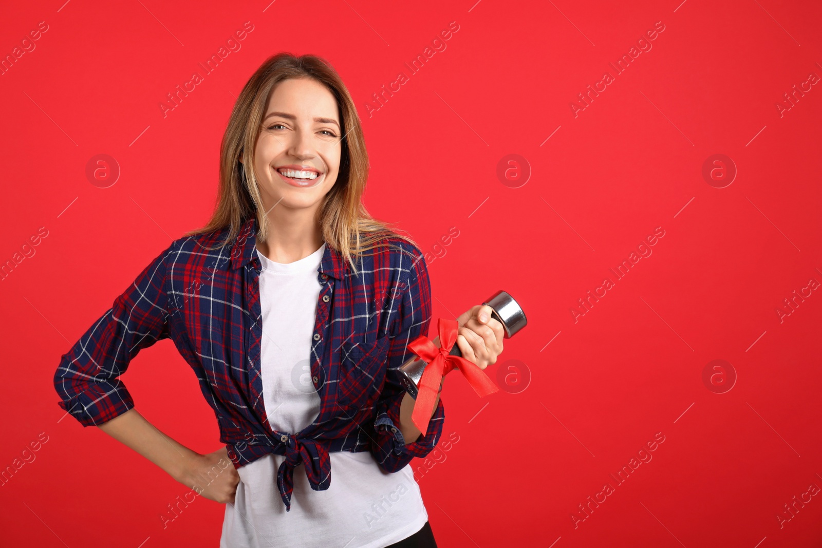 Photo of Woman with dumbbell as symbol of girl power on red background, space for text. 8 March concept