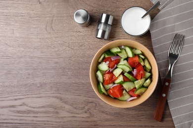 Bowl of vegetarian salad with cucumber, tomato and onion served on table, flat lay. Space for text