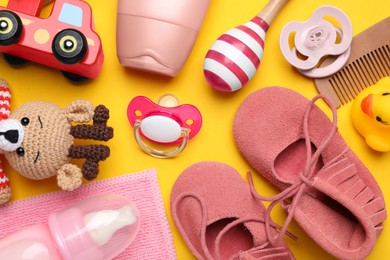 Flat lay composition with pacifiers and other baby stuff on yellow background
