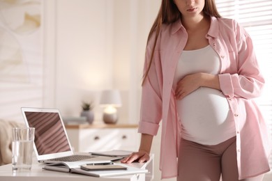 Photo of Tired pregnant woman working at home, closeup. Maternity leave