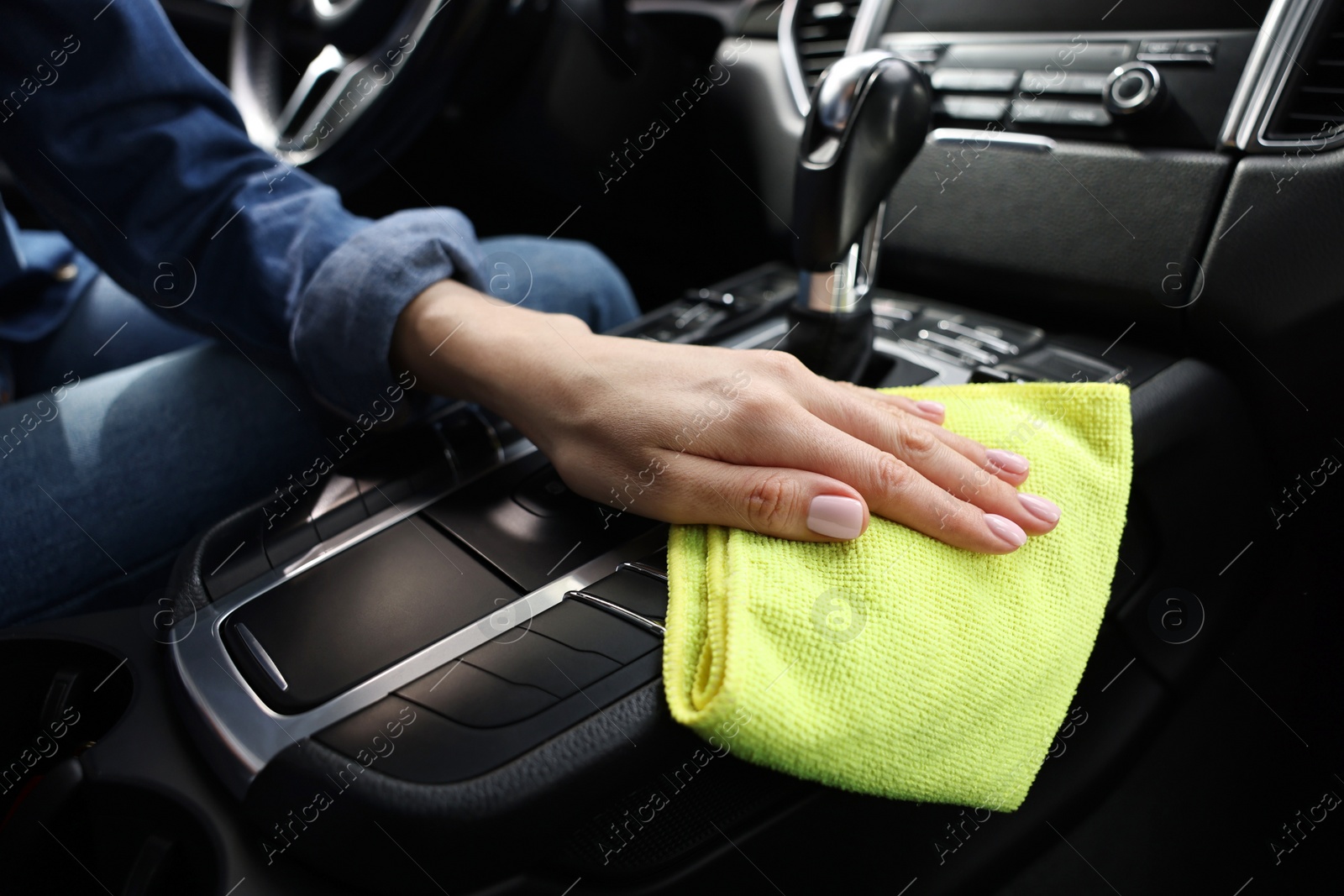 Photo of Woman wiping her modern car with rag, closeup