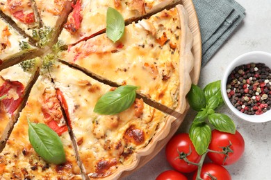 Photo of Tasty quiche with tomatoes, basil and cheese served on light textured table, flat lay