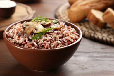 Photo of Delicious brown rice in bowl on wooden table