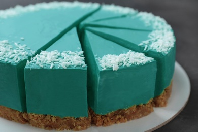 Photo of Sliced tasty spirulina cheesecake on dark grey table, closeup view