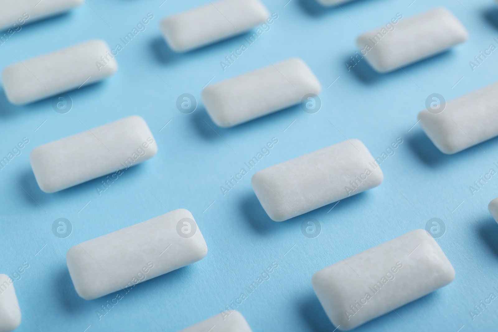 Photo of Tasty white chewing gums on light blue background