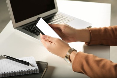 Woman using smartphone at white table, closeup