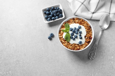 Photo of Delicious yogurt with granola and blueberries served on grey table, flat lay. Space for text