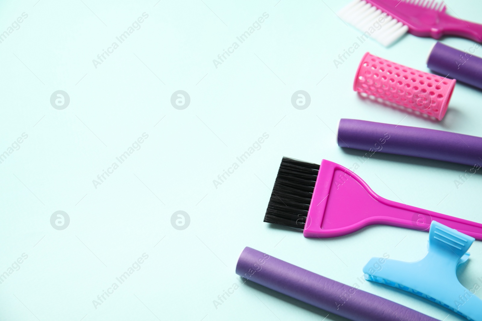 Photo of Professional tools for hair dyeing on light blue background, space for text