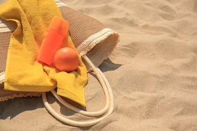 Photo of Beach bag, sunscreen and other accessories on sand. Space for text