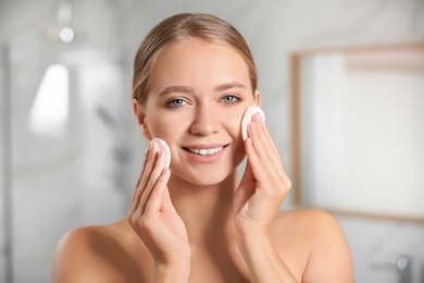 Photo of Beautiful young woman with cotton pads indoors