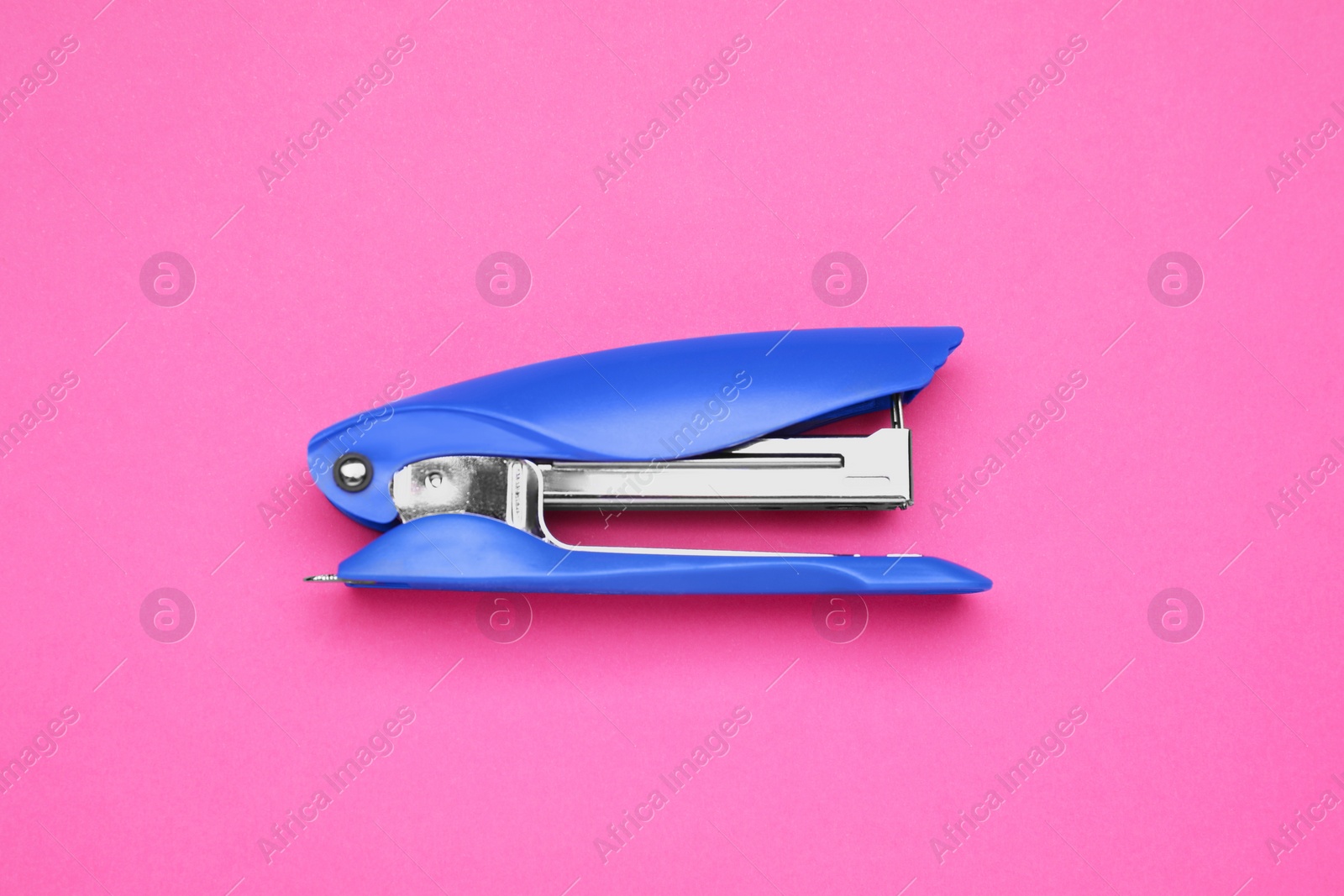 Photo of New bright stapler on pink background, top view. School stationery