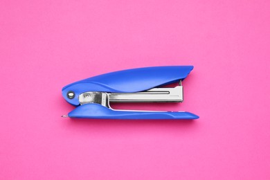 Photo of New bright stapler on pink background, top view. School stationery