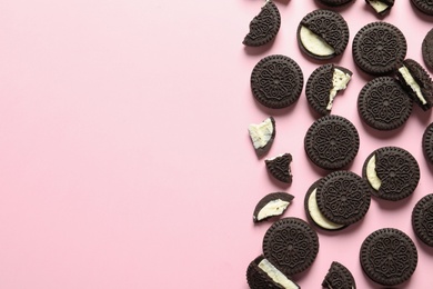 Photo of Tasty chocolate cookies with cream on color background, flat lay. Space for text