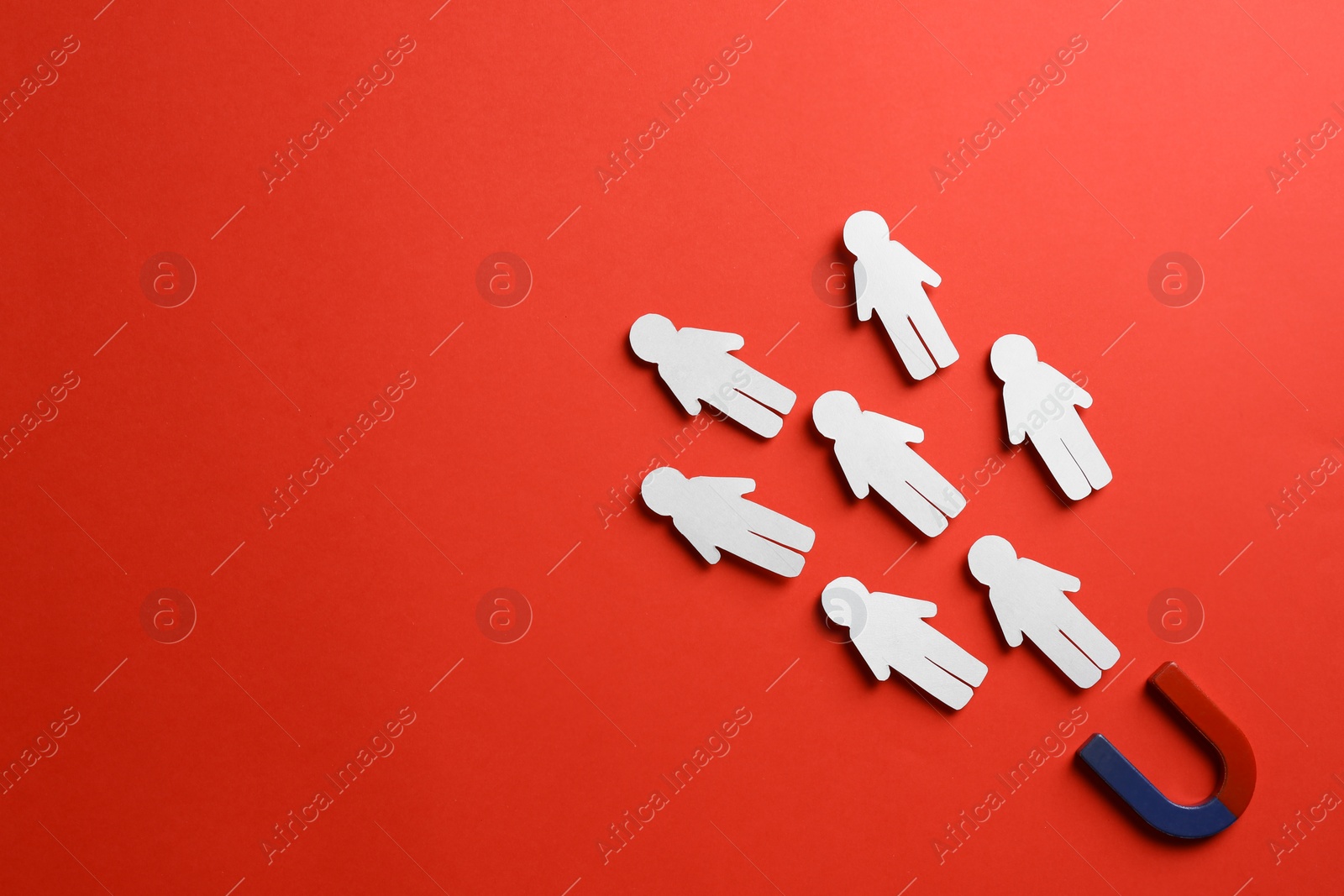 Photo of Magnet attracting paper people on red background, flat lay. Space for text