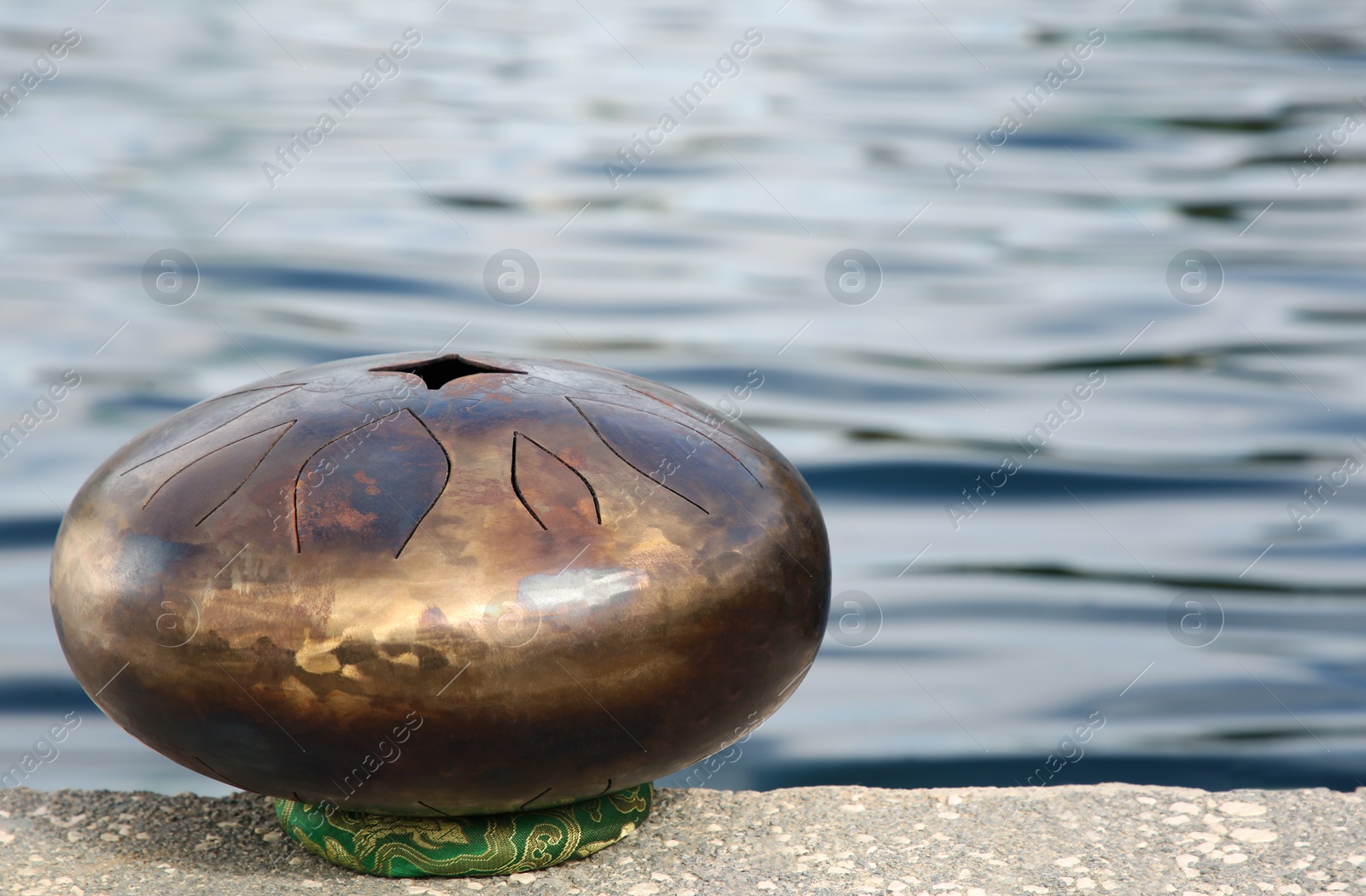 Photo of Steel tongue drum near sea, space for text. Percussion musical instrument