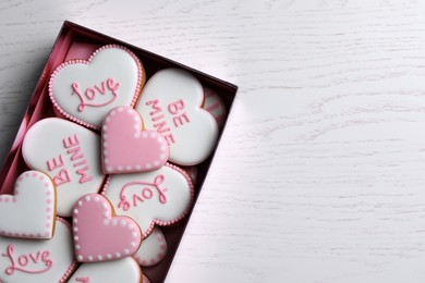 Photo of Delicious heart shaped cookies in box on white wooden table, top view. Space for text