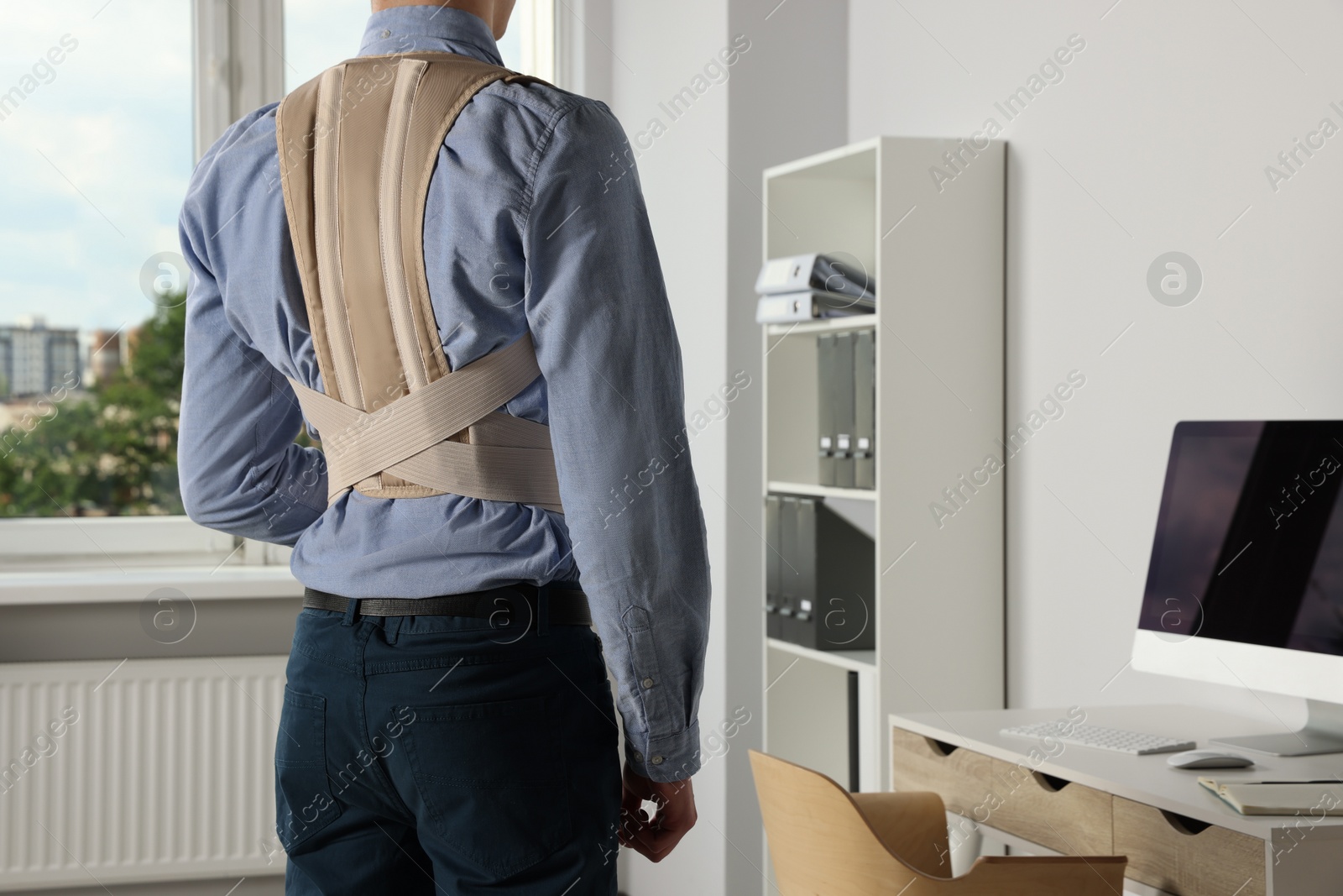 Photo of Closeup of man with orthopedic corset in room, back view