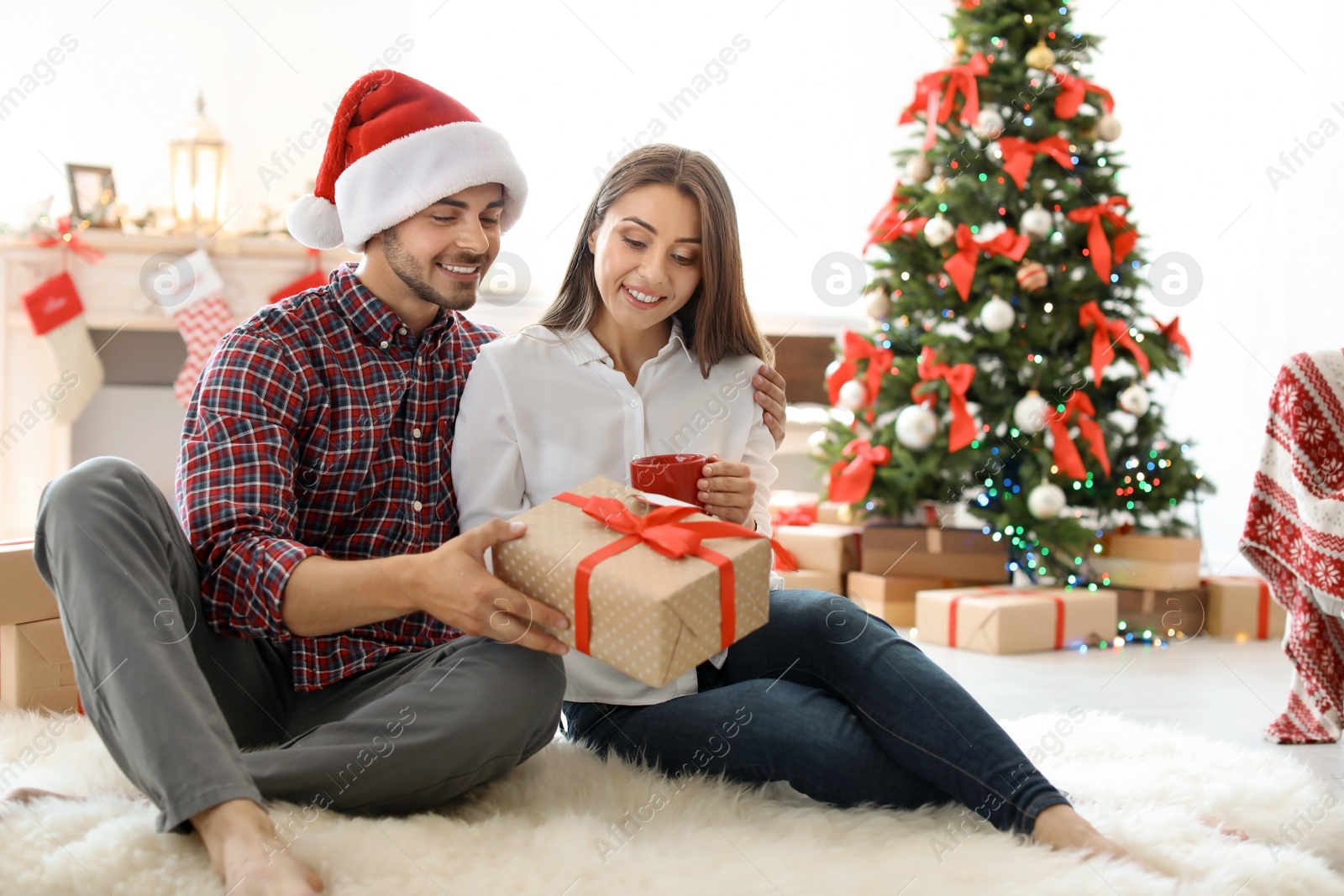 Photo of Young couple with Christmas gift at home