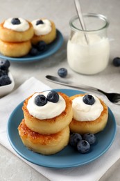 Photo of Delicious cottage cheese pancakes with blueberries, honey and sour cream on light table