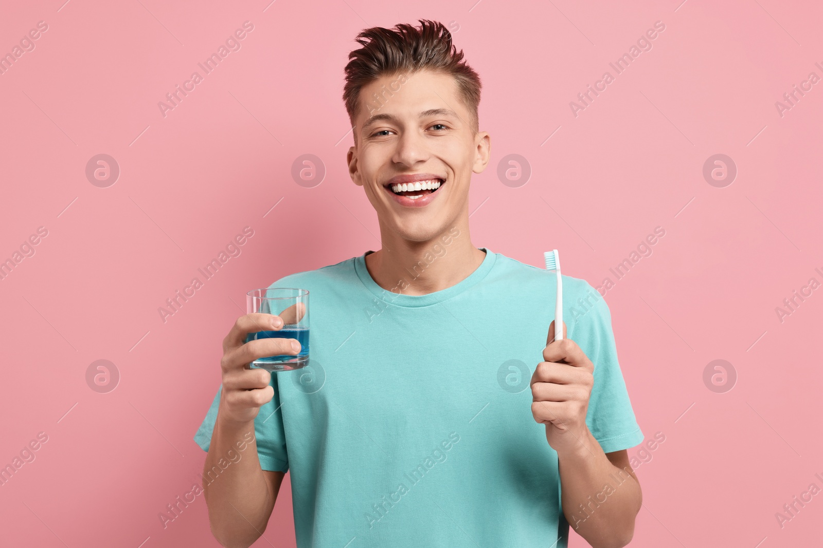 Photo of Young man with mouthwash and toothbrush on pink background