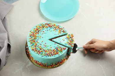 Photo of Woman taking slice of fresh delicious birthday cake at table, closeup