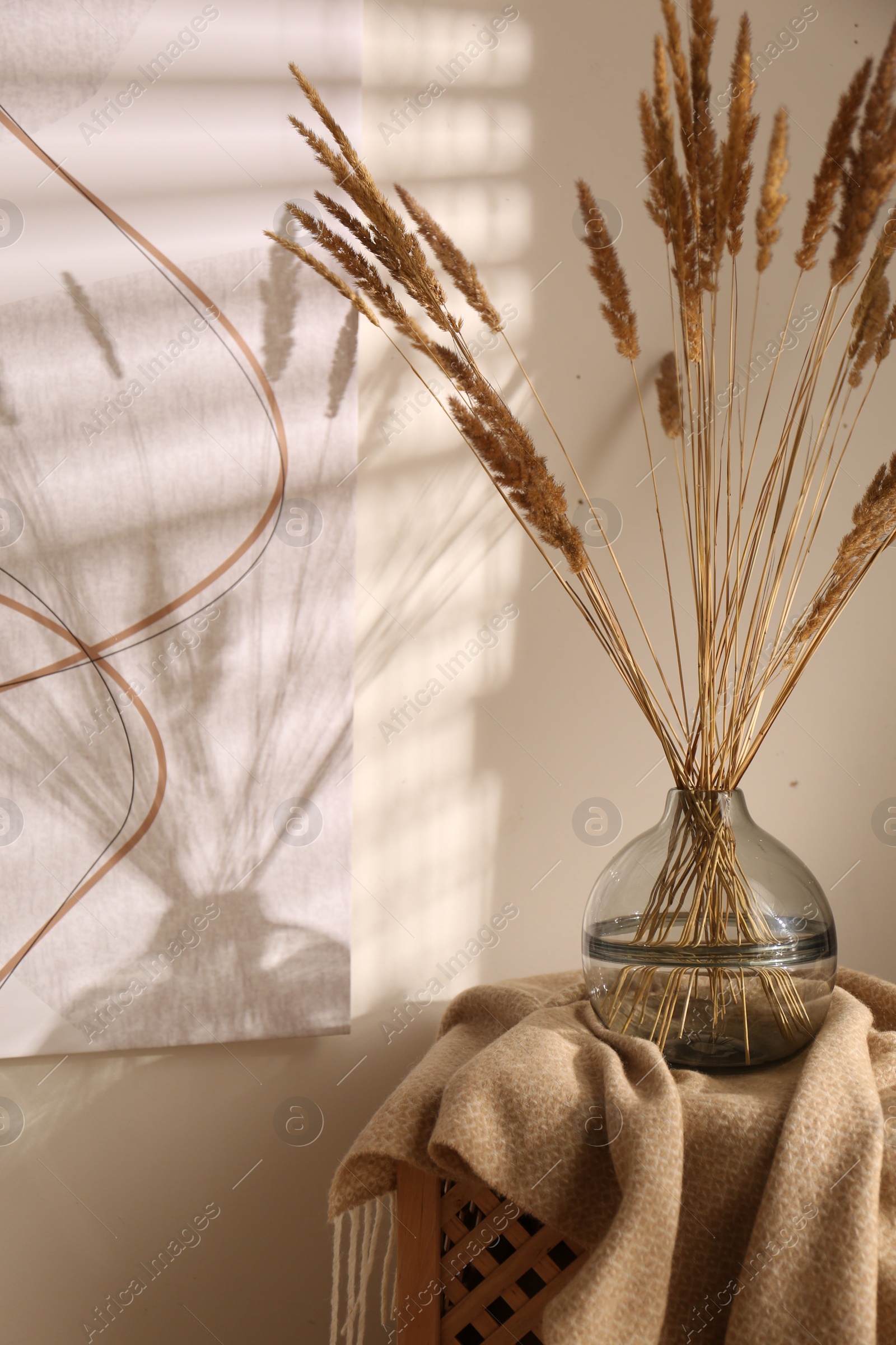 Photo of Vase with decorative dried plants and painting in stylish room interior