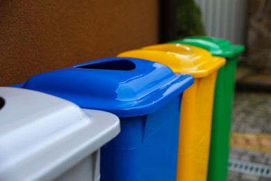 Photo of Many color recycling bins near brown wall outdoors, closeup. Space for text