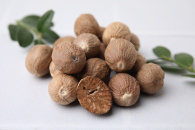 Heap of nutmegs on white table, closeup
