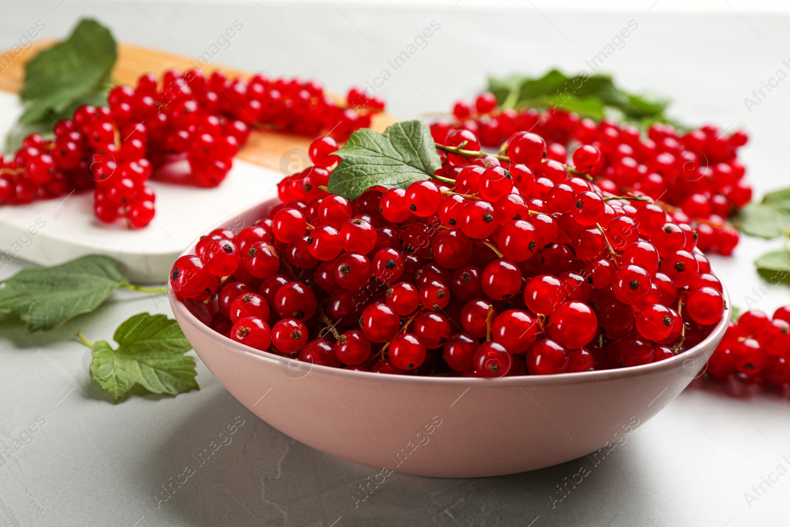 Photo of Delicious red currants in bowl on light table
