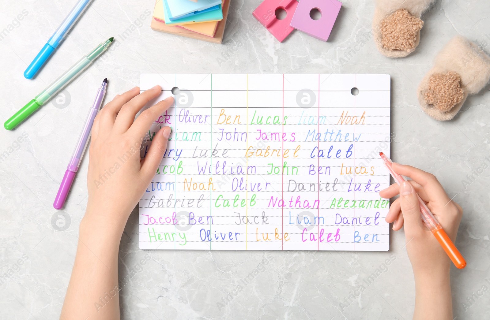 Photo of Woman choosing baby name at grey marble table, top view