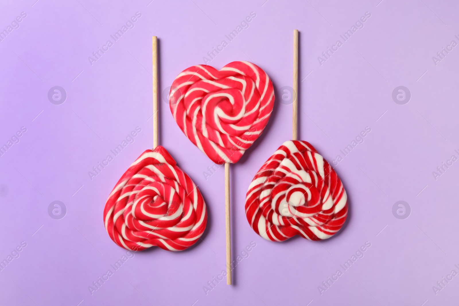 Photo of Sweet heart shaped lollipops on violet background, flat lay. Valentine's day celebration