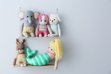 Photo of Shelf with cute toys on light wall, space for text. Child's room interior element