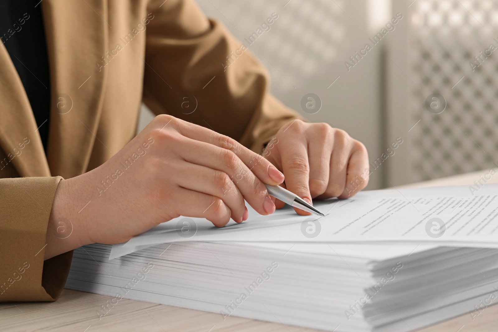 Photo of Woman signing document at wooden table, closeup