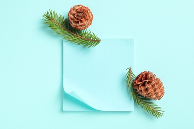 Pinecones, fir branches and notes on light blue background, flat lay. Space for text