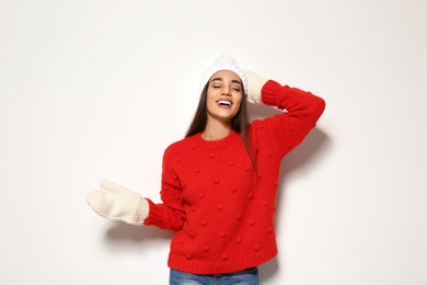 Young woman in warm sweater and hat on white background. Celebrating Christmas